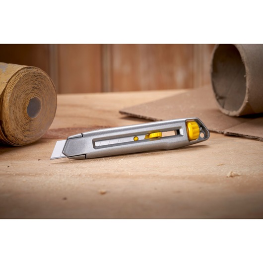 STANLEY 0-10-018 utility knife with silver body and yellow accents on a wooden surface, side view.