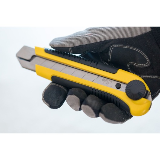 STANLEY 0-10-425 utility knife held in gloved hand, yellow and black retractable blade, side view.