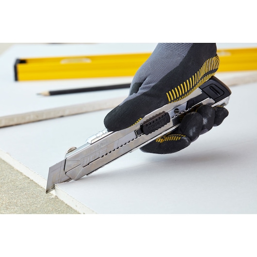 STANLEY 0-10-820 utility knife cutting drywall held by gloved hand, side angle photography.