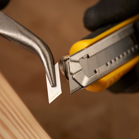 STANLEY 0-11-301 utility knife blade held by pliers, close-up, cutting tool category.