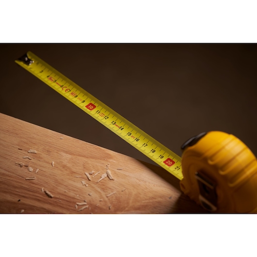 STANLEY 0-30-497 yellow tape measure extended on wood surface, close-up photography.