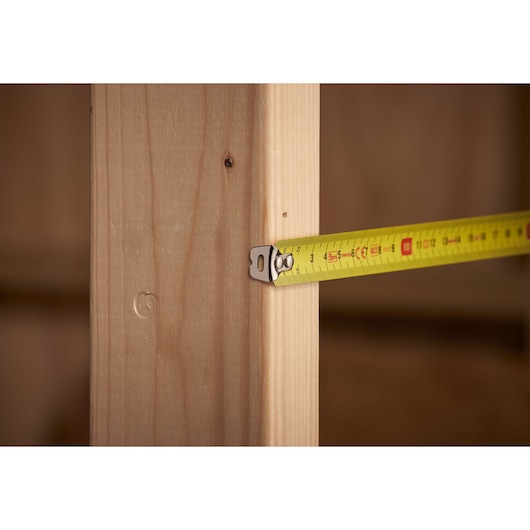 STANLEY 0-30-497 tape measure measuring wooden beam, close-up angle, yellow color, photography.