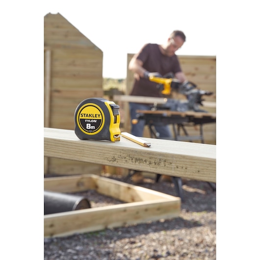 STANLEY 0-30-657 tape measure with yellow and black casing, 8m length, on timber at construction site.