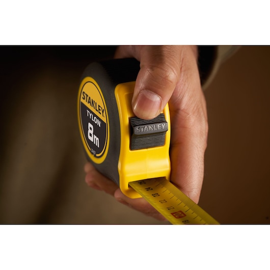 Photo of STANLEY 0-30-657 Tylon 8m tape measure in hand, showing yellow and black casing and extended blade.