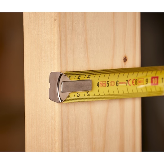 STANLEY 0-33-442 tape measure extended on wood surface, yellow blade with metric markings, close-up angle.