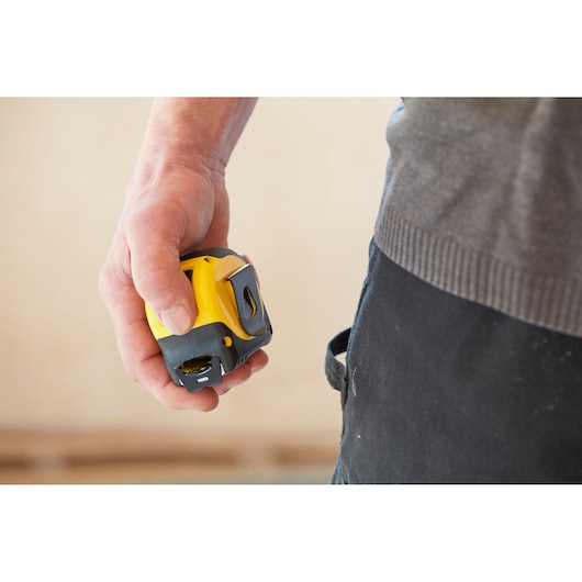 STANLEY 0-33-720 tape measure held in hand, yellow and black, close-up photography.