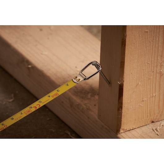 STANLEY 0-34-108 tape measure in use, hooked on wooden beam, close-up photography.