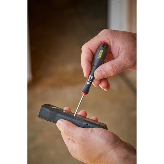 Photography of STANLEY 0-65-006 precision screwdriver held in hand, used on an electronic device.