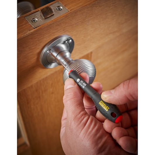 STANLEY 0-65-006 precision screwdriver in use on a metal door handle, close-up view.
