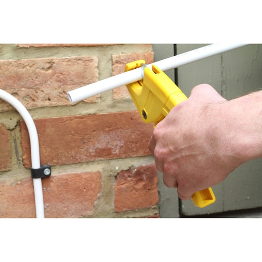 STANLEY 0-70-450 pipe cutter tool cutting white plastic pipe, close-up outdoor photography.