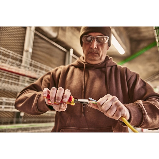 Photo of STANLEY 0-84-010 pliers being used to strip insulation from a yellow electrical cable.