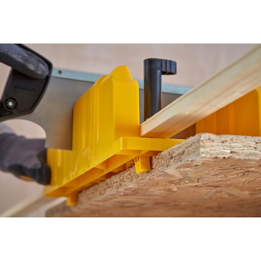 STANLEY 1-20-600 yellow plastic mitre box and saw cutting wooden board, close-up angle.