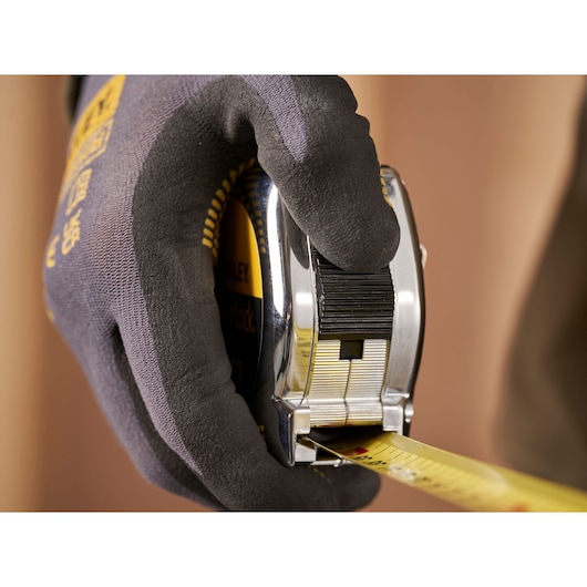 Stanley 1-33-198 tape measure held in gloved hand, close-up photography, product category: tape measure