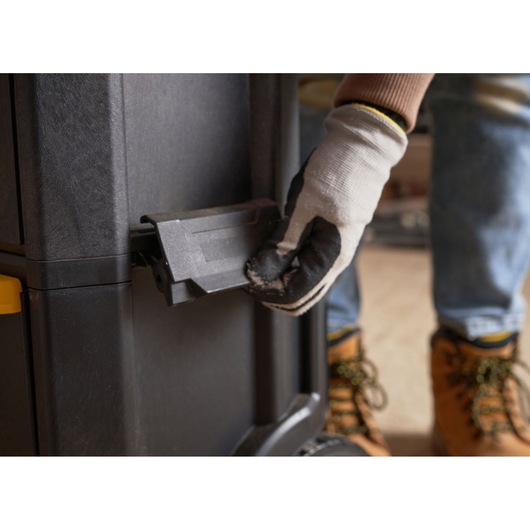 STANLEY 1-79-206 tool storage latch close-up, worker gloved hand operating black latch