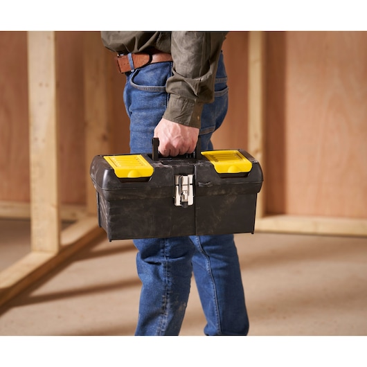 STANLEY 1-92-065 toolbox with yellow lids, carried by person in jeans, photography in workshop.