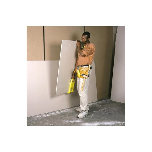 STANLEY 1-93-301 drywall carrier tool held by worker with tool belt, standing next to drywall sheets.