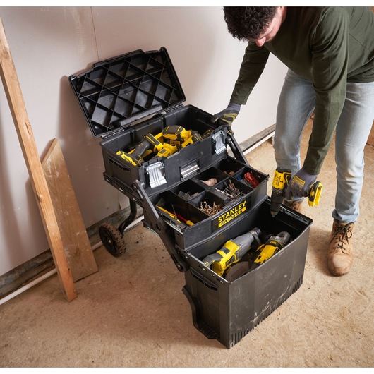 STANLEY 1-94-210 mobile tool chest with open lid showing organized power tools, fasteners, and accessories on a worksite.