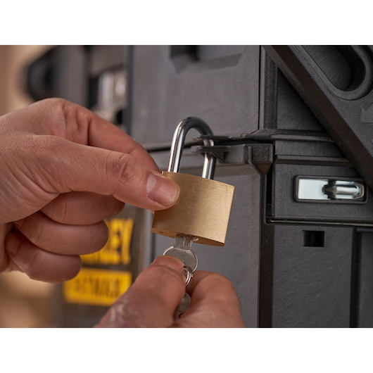STANLEY 1-94-210 padlock being unlocked with a key on a black toolbox, close-up photography.