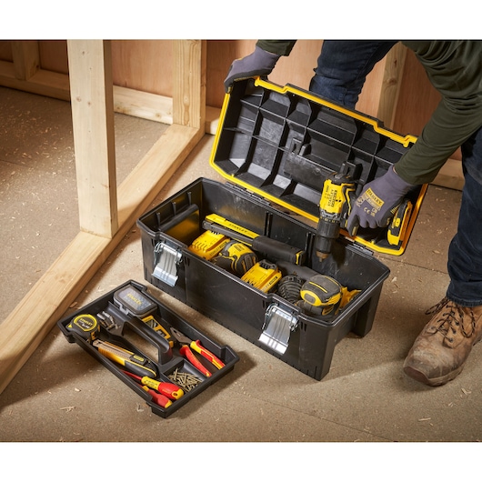 STANLEY 1-94-749 toolbox with open lid, contains assorted hand tools and accessories, shown in a workshop setting.