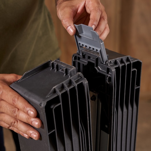 Photo of hands assembling STANLEY SKU 1-97-475 black plastic tool case with secure latch, close-up.