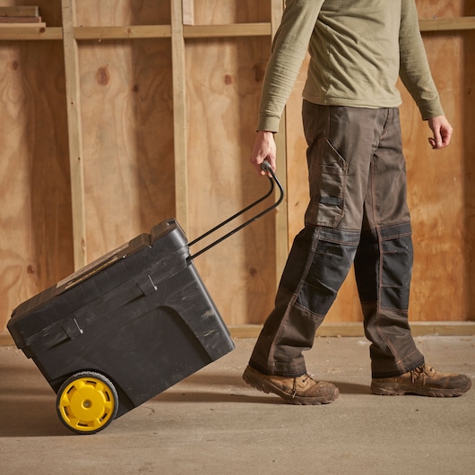 STANLEY 1-97-503 rolling tool box with yellow wheels being pulled by a person, indoor workshop setting.
