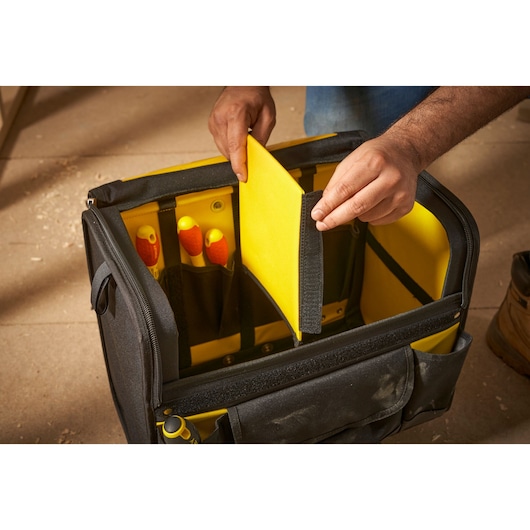 STANLEY 1-97-515 tool bag with yellow interior divider, hand holding divider, front angle.