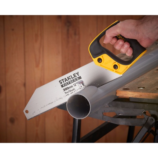 STANLEY 2-17-206 hand saw cutting plastic pipe on workbench, close-up view showing handle and blade.