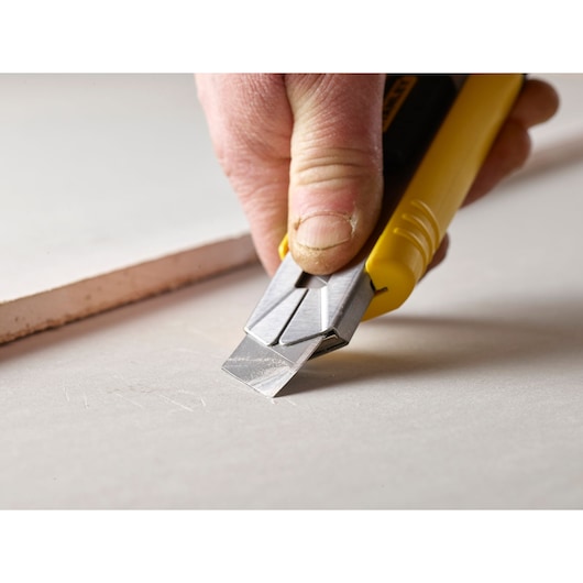 STANLEY 3-11-725 utility knife with yellow handle used to cut drywall, close-up photography.