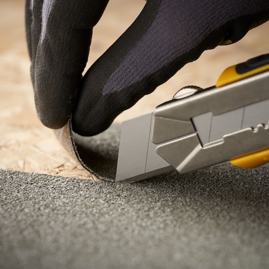 STANLEY 3-11-725 utility knife cutting roofing material, close-up with gloved hand.