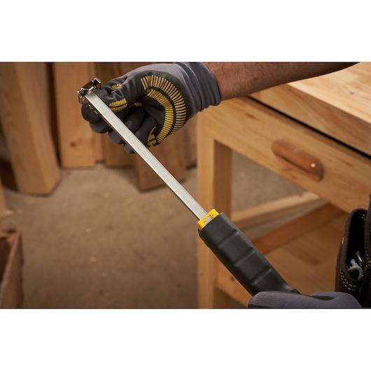 Photo of STANLEY 6-PHT150 hand staple gun in use, black and yellow handle, workshop setting.
