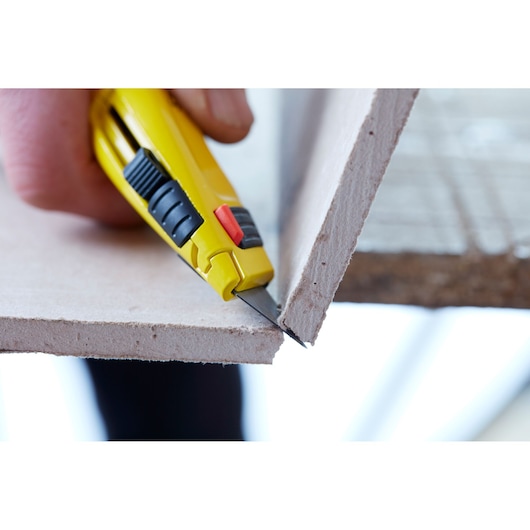 STANLEY 7-10-778 utility knife cutting drywall, close-up view.