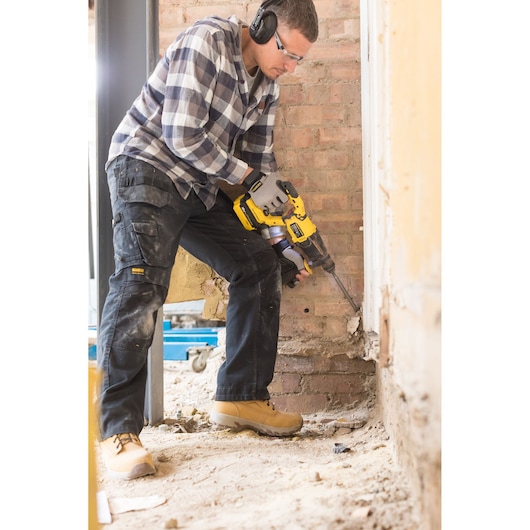 STANLEY FMCD900B hammer drill in use on a construction site, worker drilling into a brick wall.