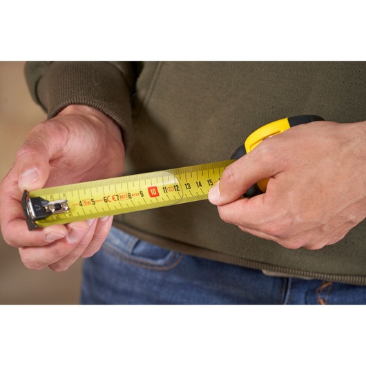 STANLEY FMHT0-33864 tape measure in use, close-up showing yellow tape and clear markings.