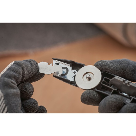 STANLEY FMHT10500-0 utility knife close-up showing blade change with gloved hands.