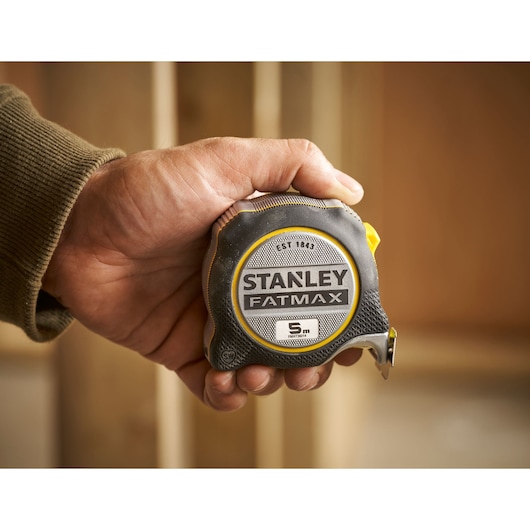 Photo of STANLEY FMHT38214-0 FATMAX tape measure, 5m, black and yellow, held in hand.