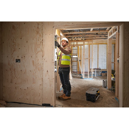 STANLEY FMHT43675-1 spirit level used by worker on wooden door frame at construction site.