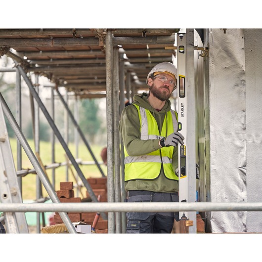 STANLEY FMHT43677 spirit level used by worker in high-visibility vest at construction site.