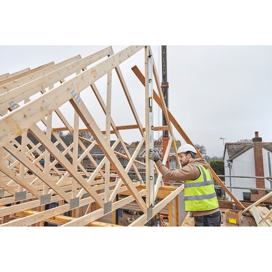 STANLEY FMHT43679-1 spirit level used by worker in high-visibility vest at construction site with timber framing.