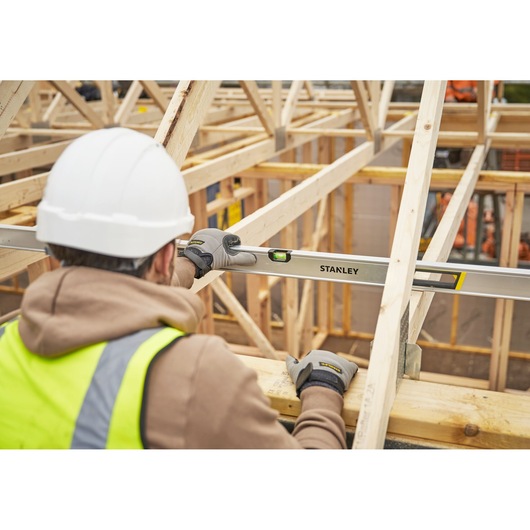 Photo of worker using STANLEY FMHT43680-1 spirit level on wooden frame at construction site.
