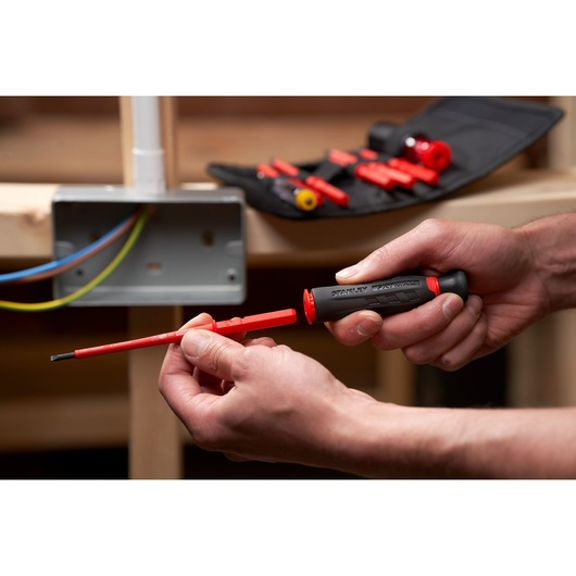 STANLEY FMHT66426-0 insulated screwdriver kit in use, featuring red interchangeable bits and pouch.