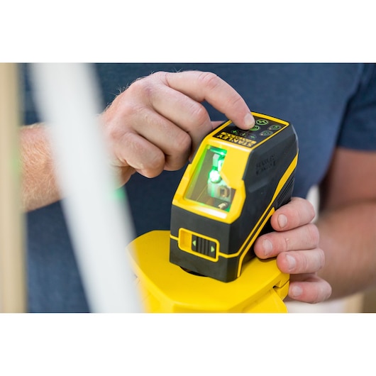 Photo of STANLEY FMHT77586-1 laser level in use, yellow and black handheld tool with digital controls.
