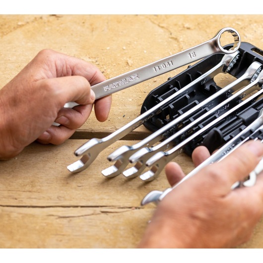 STANLEY FMMT82844-0 wrench set photography, hand holding silver wrenches on wooden surface.