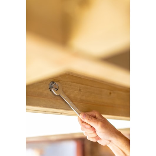 STANLEY FMMT82845-0 ratcheting wrench tightening bolt on wooden beam, hand holding tool.