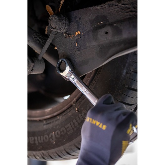 Photo of STANLEY FMMT82849-0 ratcheting wrench in use on car suspension bolt, mechanic wearing STANLEY gloves.