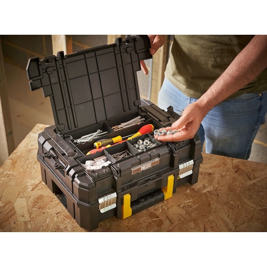 STANLEY FMST1-71967 toolbox with open lid, showing compartments with tools and hardware, on a workbench.