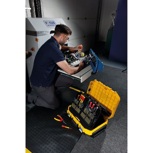 STANLEY FMST1-72383 toolbox with organized hand tools, open on the floor near technician repairing equipment.