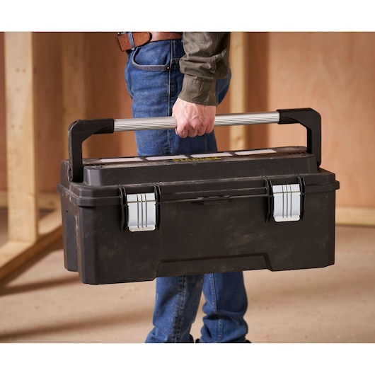 STANLEY FMST1-75791 toolbox with silver metal handle and latches carried indoors by person wearing jeans.