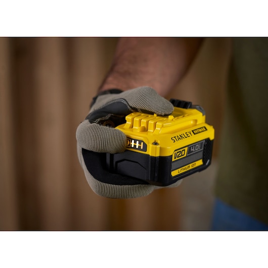 Photo of STANLEY SFMCB14M1 V20 4.0Ah lithium-ion battery held in a gloved hand.