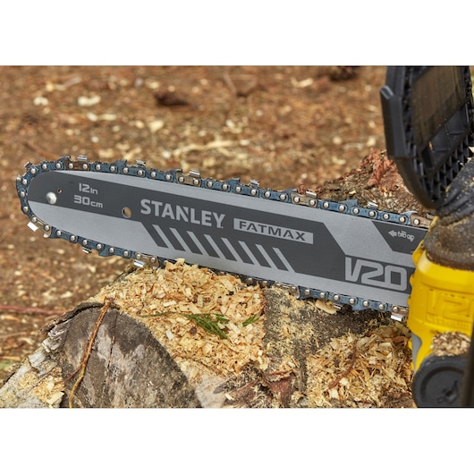 STANLEY SFMCCS630M1 chainsaw close-up, 12in bar cutting wood, FATMAX V20 branding visible.