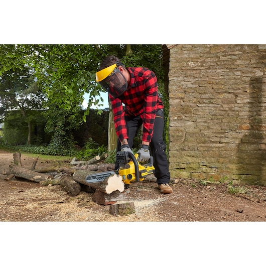 STANLEY SFMCCS630M1 chainsaw in use outdoors, cutting wood, man wearing safety gear.